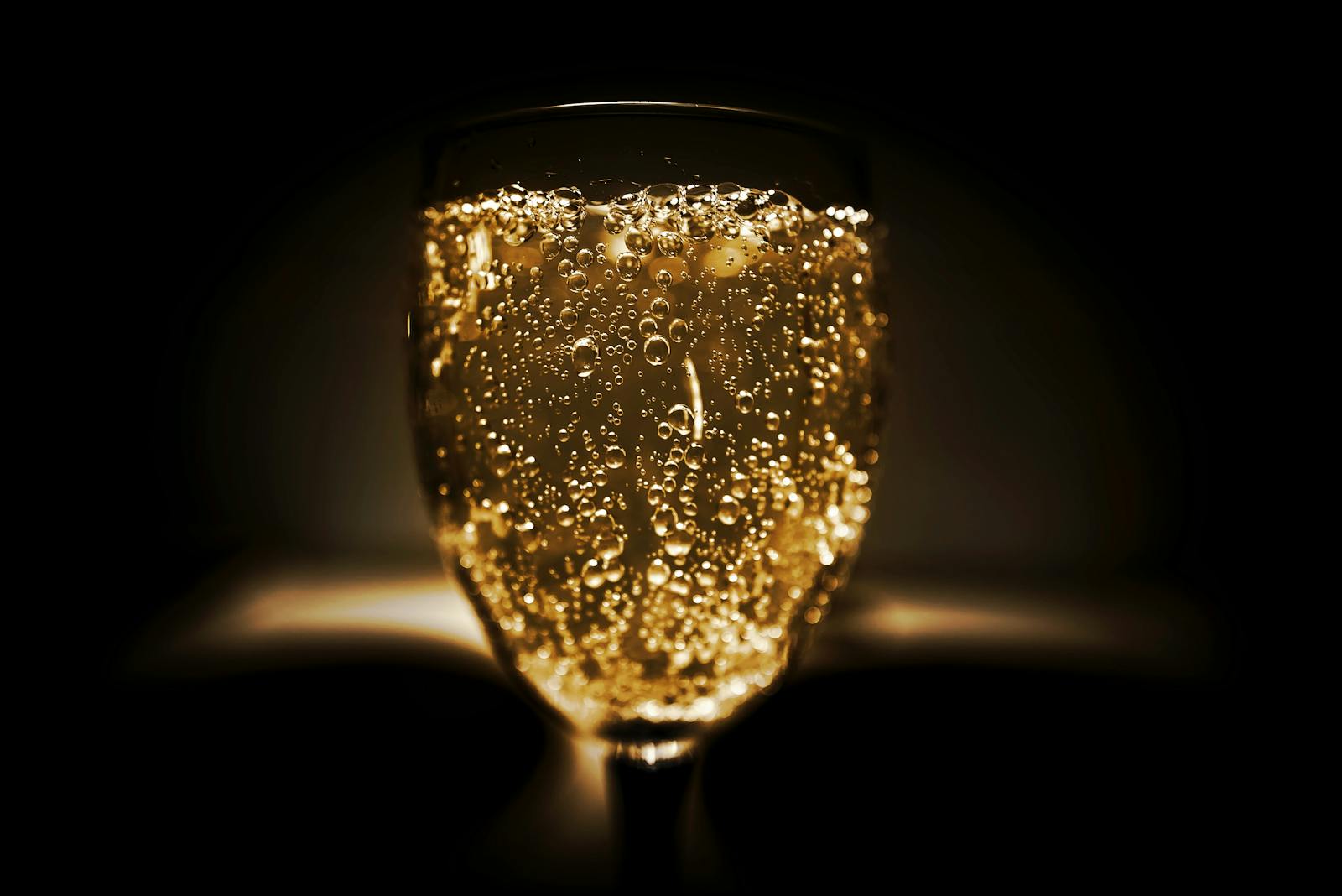 Elegant close-up of a champagne glass with bubbles against a dark background, perfect for celebrations.