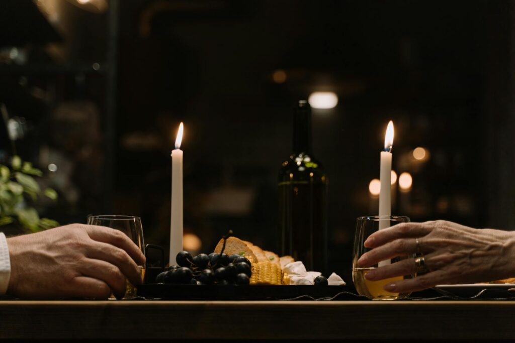 Intimate dinner setup with wine, cheese, and candles on a wooden table.