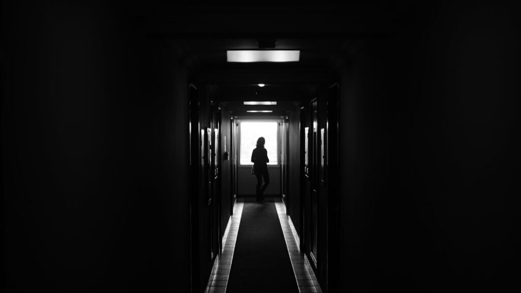 Dramatic silhouette of a figure in a dimly lit hallway, creating a sense of mystery.