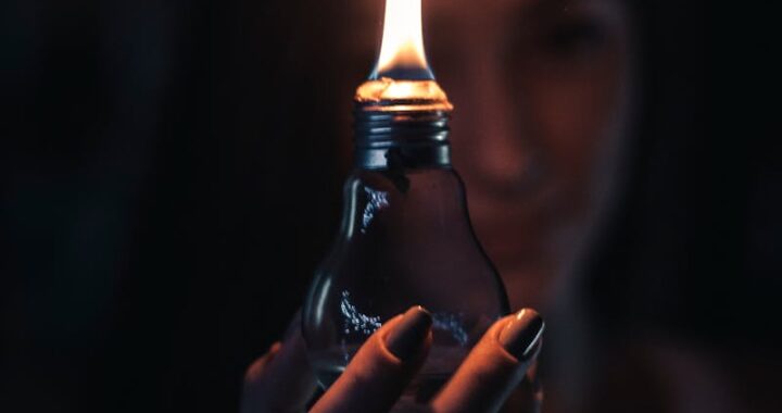 A glowing flame inside a light bulb held by a woman, creating a warm and mysterious ambiance.