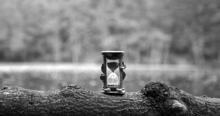 grayscale photo of hour glass on rock
